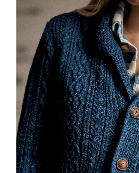 Cable-knit cardigan made with cotton and semi-worsted wool. Designed with a shawl collar and accented with waist patch pockets. Finished with genuine horn buttons.