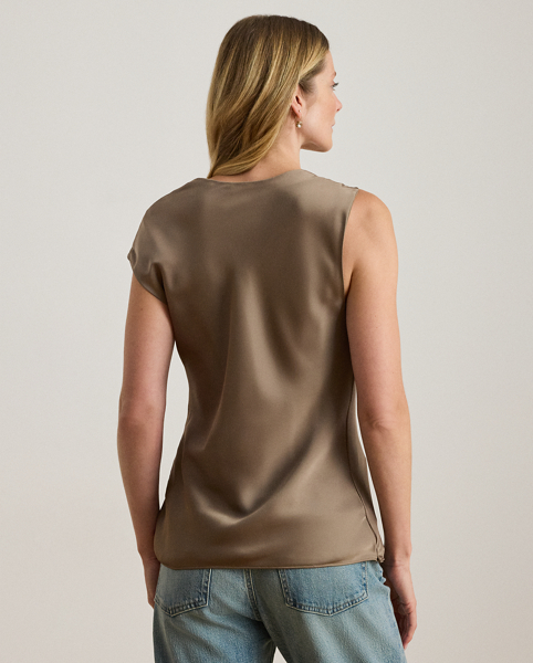 Beautifully draped in glossy satin charmeuse, this blouse features an asymmetrical design with one cap sleeve and a twisted strap. A keyhole detail and pleats at the strap complete the look.