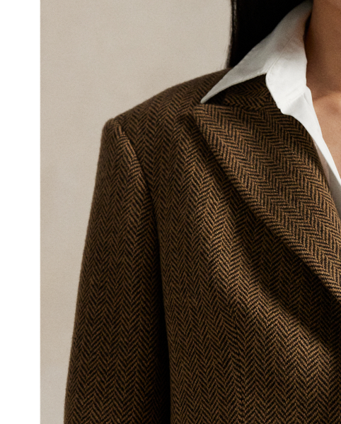 Tailored in Portugal, this coat showcases refined herringbone tweed and minimalist design elements – from its single-button closure and clean-lined silhouette to its classic peak lapels.