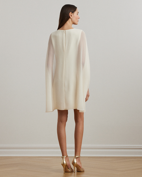 Turn heads at your next event in this glamorous cocktail dress, which is designed with a cascading, semi-sheer cape overlay and a figure-defining sheath silhouette.