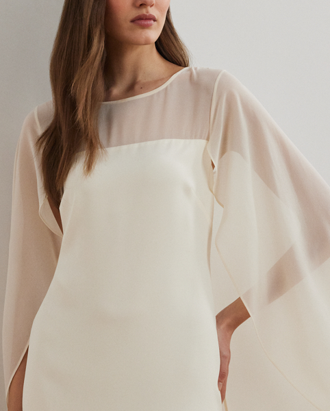 Turn heads at your next event in this glamorous cocktail dress, which is designed with a cascading, semi-sheer cape overlay and a figure-defining sheath silhouette.