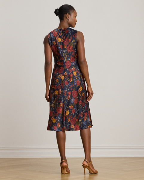 Satin charmeuse brings a beautiful sheen and graceful drape to this sleeveless cocktail dress, which depicts the season's painterly florals against a navy backdrop. Pleats on the shoulder provide an elegant finish.