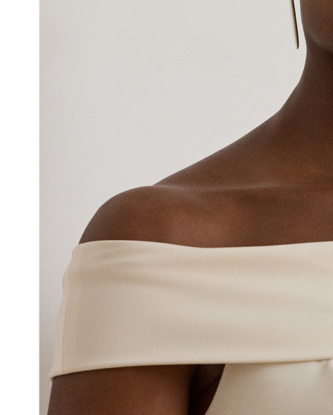 Evoking timeless glamour, this off-the-shoulder gown is designed with thoughtfully placed vertical seams, which accentuate its statuesque column silhouette. A slit on the skirt and smooth, stretch-infused crepe afford ease of movement.