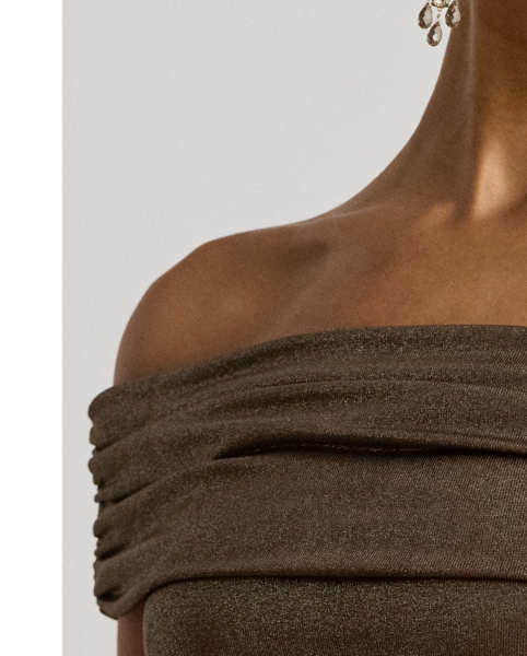 This cocktail dress pairs metallic foiled jersey with a ruched off-the-shoulder bodice and a flared skirt, making this style a striking choice for special occasions.