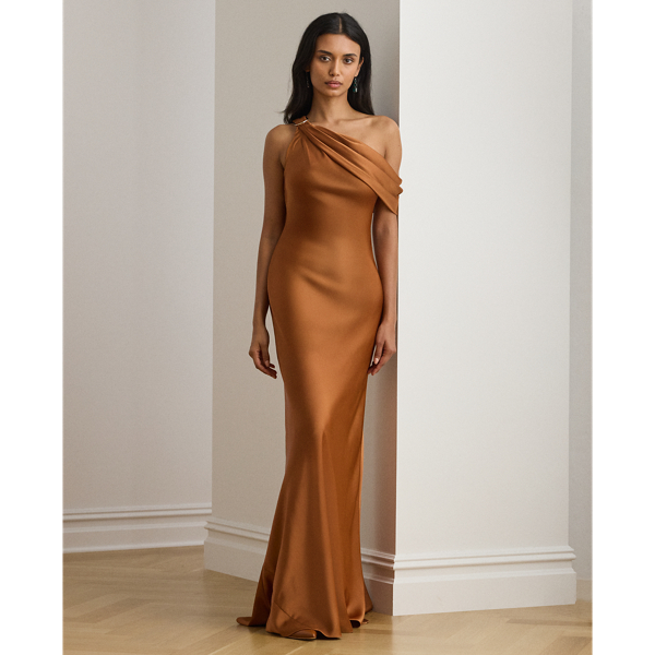 Crisp pleats complement the asymmetrical off-the-shoulder neckline of this floor-length gown, which is beautifully draped in satin charmeuse for a lustrous sheen. A horseshoe-shaped buckle on the shoulder pays homage to  Ralph Lauren Lauren's iconic equestrian-inspired heritage.