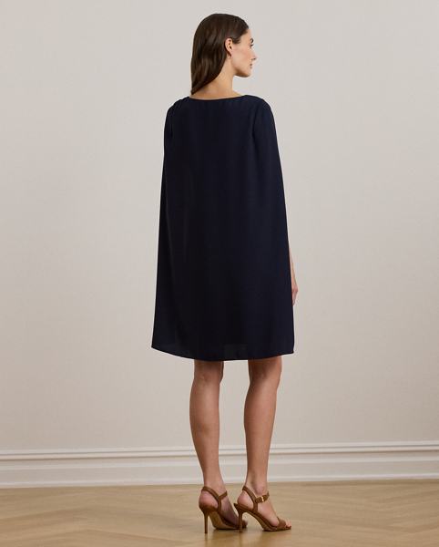 A stylish choice for special occasions, this modern georgette cocktail dress is elevated by a cascading cape, which adds fluid movement to its body-hugging silhouette.