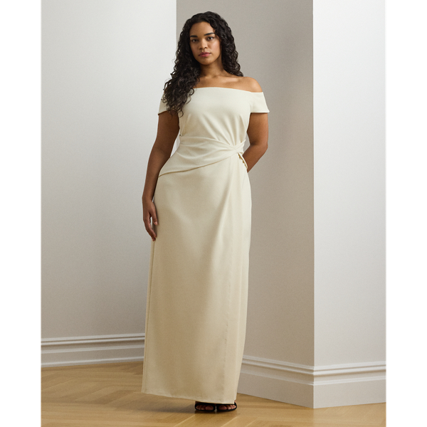 Crafted with smooth crepe for a fluid drape and a luxurious sensibility, this gown is designed with an elegant off-the-shoulder silhouette and a chic twist detail on the waist. A slit in the skirt creates ease of movement.