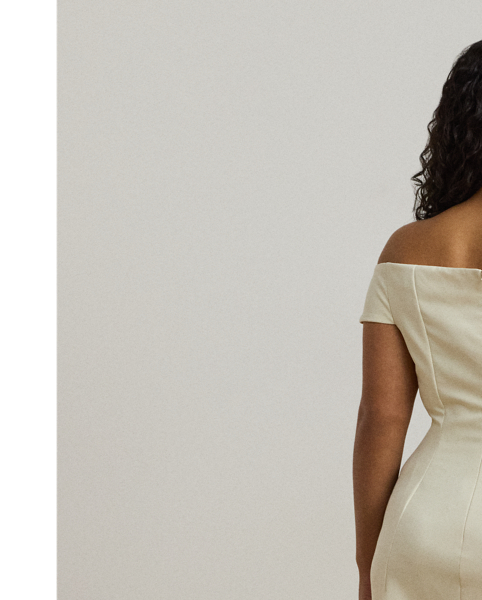 Crafted with smooth crepe for a fluid drape and a luxurious sensibility, this gown is designed with an elegant off-the-shoulder silhouette and a chic twist detail on the waist. A slit in the skirt creates ease of movement.