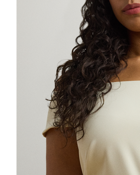 Crafted with smooth crepe for a fluid drape and a luxurious sensibility, this gown is designed with an elegant off-the-shoulder silhouette and a chic twist detail on the waist. A slit in the skirt creates ease of movement.