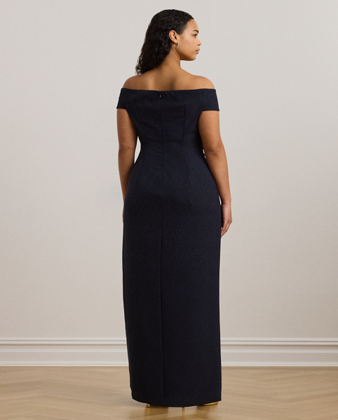 Crafted with smooth crepe for a fluid drape and a luxurious sensibility, this gown is designed with an elegant off-the-shoulder silhouette and a chic twist detail on the waist. A slit in the skirt creates ease of movement.
