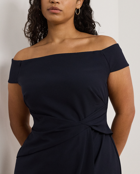 Crafted with smooth crepe for a fluid drape and a luxurious sensibility, this gown is designed with an elegant off-the-shoulder silhouette and a chic twist detail on the waist. A slit in the skirt creates ease of movement.