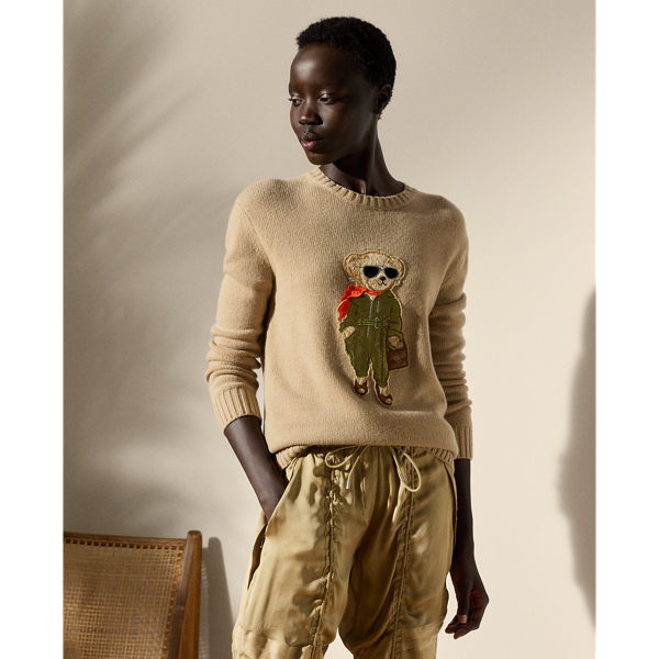 This lofty cashmere jumper depicts the Polo Bear in an outfit informed by the utility-inspired aesthetic of Pre-Spring 2025 Collection. A master embroiderer created the season’s Aviator Polo Bear from highly considered materials, including stretch silk charmeuse for the vibrant orange scarf, metallic satin for the jumpsuit, lambskin for the RL 888 bag and metallic thread for the jumpsuit zips, the bag’s “RL” hardware and the belt buckle. Hot-fixed rhinestones for the earrings complete the bear’s chic look.