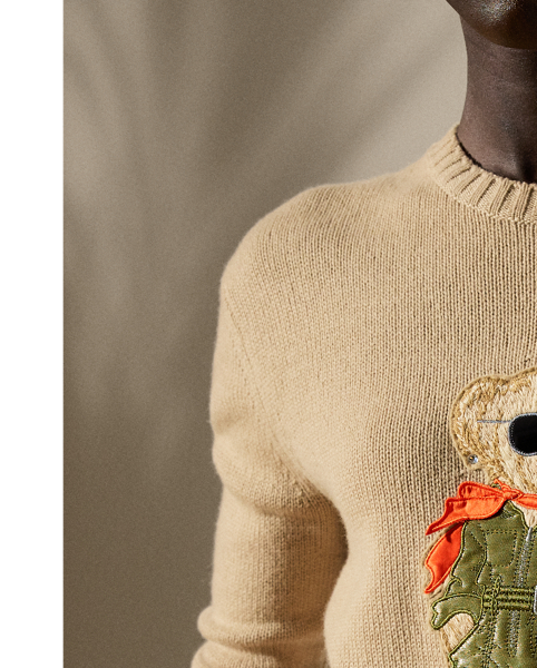 This lofty cashmere jumper depicts the Polo Bear in an outfit informed by the utility-inspired aesthetic of Pre-Spring 2025 Collection. A master embroiderer created the season’s Aviator Polo Bear from highly considered materials, including stretch silk charmeuse for the vibrant orange scarf, metallic satin for the jumpsuit, lambskin for the RL 888 bag and metallic thread for the jumpsuit zips, the bag’s “RL” hardware and the belt buckle. Hot-fixed rhinestones for the earrings complete the bear’s chic look.