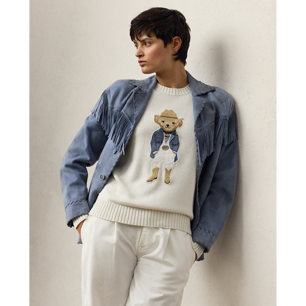 Capturing the relaxed sophistication of the Hamptons, the Spring 2025 Collection's blue-and-white colour palette nods to the interplay between sky and sea, which is brought to life here in the season's lofty silk Polo Bear jumper. Donning an outfit informed by Mr Lauren's penchant for Western style, the Hamptons Spring Polo Bear was created by a master embroiderer from highly considered materials, including rustic lamb suede for the season's Western-inspired Rennie jacket, silk jersey for the striped T-shirt, cotton broadcloth for the shirt, washed linen-blend canvas for the trousers, silk double georgette for the bandanna, dry-cleanable lamb suede for the cowboy boots and cowboy hat, and metallic thread for the  Ralph Lauren Lauren Collection's signature rodeo-buckle belt.