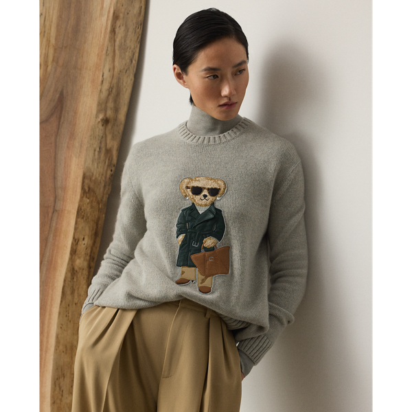 This lofty cashmere jumper depicts the Polo Bear in an outfit informed by the understated elegance that defines Pre-Autumn 2025 Collection. A team of six master embroiderers created the season's Racing Green Trench Polo Bear with highly considered materials, including synthetic leather for the bear's shoes, Ralph Lauren Tote and trench coat – whose colour is directly inspired by one of Mr Lauren's iconic vehicles – wool trench for the trousers, rib-knit silk-cotton for the roll neck and hot-fixed crystals for the diamond earrings.