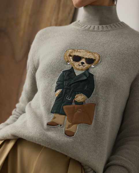 This lofty cashmere jumper depicts the Polo Bear in an outfit informed by the understated elegance that defines Pre-Autumn 2025 Collection. A team of six master embroiderers created the season's Racing Green Trench Polo Bear with highly considered materials, including synthetic leather for the bear's shoes, Ralph Lauren Tote and trench coat – whose colour is directly inspired by one of Mr Lauren's iconic vehicles – wool trench for the trousers, rib-knit silk-cotton for the roll neck and hot-fixed crystals for the diamond earrings.