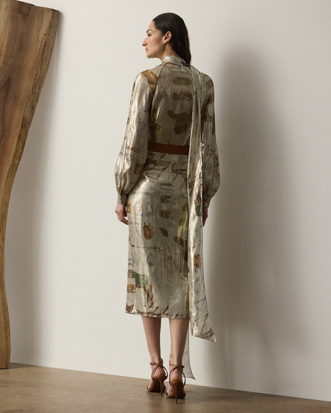 The Terry cocktail dress nods to traditional riding attire – an enduring source of inspiration for Mr Lauren since his earliest designs. Crafted from shimmering, silver-tone lamé fabric, this lean wrap dress is printed with the season's all-over equestrian-inspired motif in a renowned Italian mill in Como and designed with an array of romantic elements, including an engineered scarf, blouson sleeves and genuine mother-of-pearl buttons.