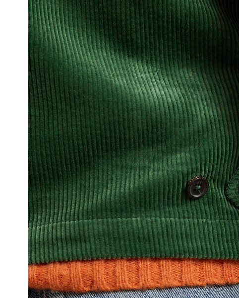 This cotton jacket contrasts the sporty silhouette of a windbreaker with the rustic texture of wide-wale corduroy. It is dyed in a custom-developed colour and finished with considered details, such as tartan-inspired lining and leather accents.